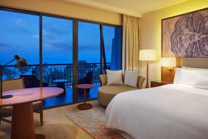 a bedroom with a bed and a table and a balcony at The Westin Desaru Coast Resort in Desaru