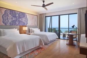 two beds in a hotel room with a view at The Westin Desaru Coast Resort in Desaru