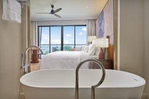 a bath tub in a bedroom with a bed and a window at The Westin Desaru Coast Resort in Desaru