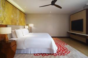 a bedroom with a white bed and a flat screen tv at The Westin Desaru Coast Resort in Desaru