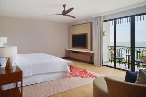 a bedroom with a bed and a tv and a balcony at The Westin Desaru Coast Resort in Desaru
