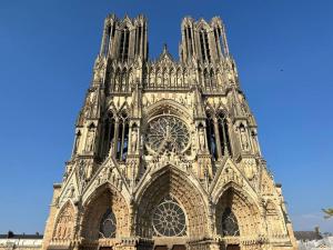 een grote kathedraal met een blauwe lucht op de achtergrond bij Hermès - Reims en grand in Reims