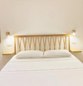 1 cama con sábanas blancas y cabecero de madera en CASA SACURI, en Rudalza