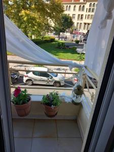 a balcony with two potted plants and a car on a street at Retro Central in Thessaloniki
