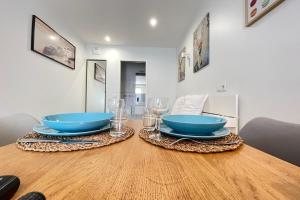 een houten tafel met twee blauwe kommen en glazen erop bij Cocoon Appart Massy N5 proche Orly in Massy