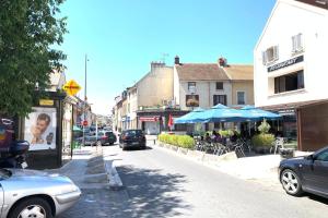 een straat met geparkeerde auto's, tafels en blauwe parasols bij Cocoon Appart Massy N5 proche Orly in Massy