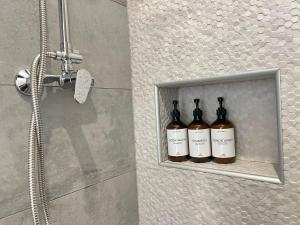tres botellas de vino sentadas en un estante en una ducha en Apartman Mara en Mala Subotica
