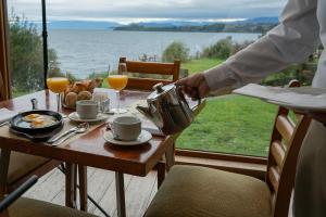 a person pouring coffee on a table with a view of the ocean at Hotel Cumbres Puerto Varas in Puerto Varas
