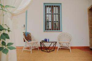 Duas cadeiras e uma mesa num quarto com uma janela em Palacete del Águila em Córdoba
