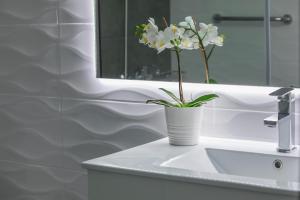 a white vase with white flowers on a bathroom sink at Blazer Residence in Larnaka