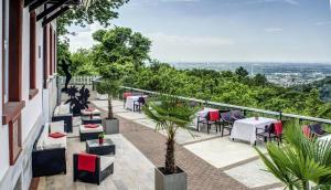 a patio with tables and chairs on a balcony at Schlosshotel Molkenkur in Heidelberg