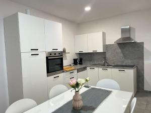 a kitchen with white cabinets and a table with a vase of flowers at Apartman Mara in Mala Subotica