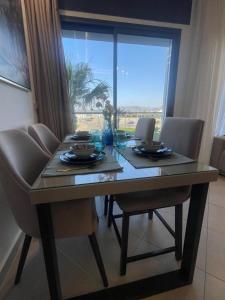 une table à manger avec des chaises et une grande fenêtre dans l'établissement Al amirat martil luxury, à Martil