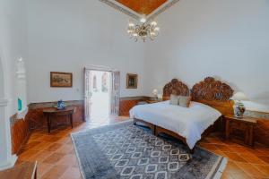 - une chambre avec un grand lit et un lustre dans l'établissement Hotel Hacienda La Cieneguita, à San Miguel de Allende