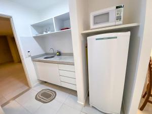 a small kitchen with a refrigerator and a microwave at Fusion Acomodação Particular na Asa Norte ao Lado do SHOPPING CONJUNTO NACIONAL com Garagem - 7º andar in Brasilia