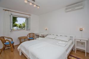 - une chambre blanche avec un grand lit et deux chaises dans l'établissement Apartments Jelen, à Dubrovnik