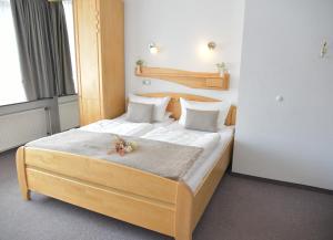 sypialnia z drewnianym łóżkiem z białą pościelą i poduszkami w obiekcie Pension Haus Bambi w mieście Mölln