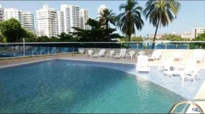 a large swimming pool with white chairs and buildings at Apartamento con vista al laguito y al mar in Cartagena de Indias