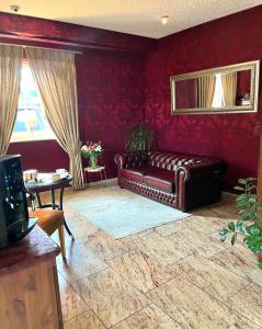 ein Ledersofa im Wohnzimmer mit roten Wänden in der Unterkunft Garni Hotel Henn in Simmerath