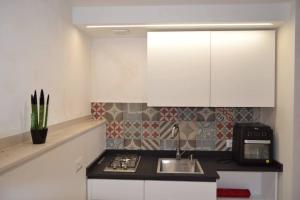 a kitchen with a sink and a stove and white cabinets at Casa vacanze TRINISULA Sicily home in Scicli