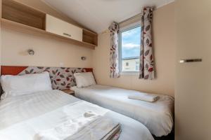 Duas camas num pequeno quarto com uma janela em Pass the Keys Wilksworth - Lovely 2 bedroom caravan in a perfect location em Wimborne Minster