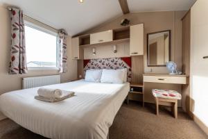 um quarto com uma grande cama branca e uma janela em Pass the Keys Wilksworth - Lovely 2 bedroom caravan in a perfect location em Wimborne Minster