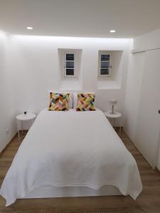 - une chambre blanche avec un lit blanc et 2 tables dans l'établissement Heart of Lisbon - Bica Apartamentos, à Lisbonne