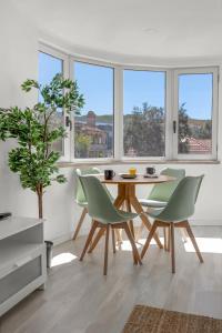 uma sala de jantar com mesa, cadeiras e janelas em Bright Alges Apartment em Algés