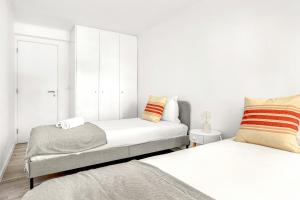 Bright Alges Apartment في ألجيس: غرفة نوم بسريرين وبجدران بيضاء
