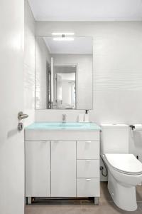 uma casa de banho branca com um lavatório e um WC em Bright Alges Apartment em Algés