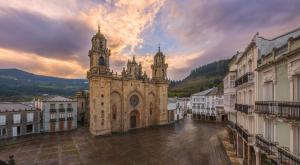 an old building with a clock tower in a city at Santa Emilia in Mondoñedo