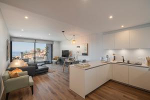 een keuken en een woonkamer met een bank en een tafel bij OurMadeira - Bayside Apartment in Câmara de Lobos