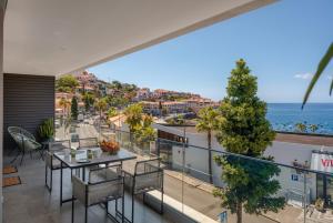 een balkon met een tafel en stoelen en uitzicht op de oceaan bij OurMadeira - Bayside Apartment in Câmara de Lobos