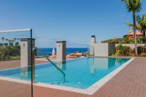 een zwembad met de oceaan op de achtergrond bij OurMadeira - Bayside Apartment in Câmara de Lobos