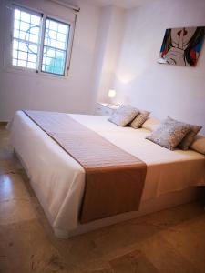 um quarto com uma cama grande e 2 almofadas em BAVIERA GOLF APARTAMENTO TERRAZA Y JARDIN em Caleta de Velez