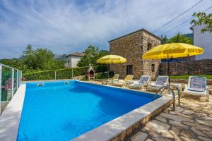 une piscine avec deux parasols et des chaises ainsi qu'une maison dans l'établissement House Katica, à Grižane