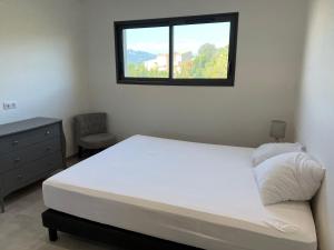 ein Schlafzimmer mit einem weißen Bett und einem Fenster in der Unterkunft LOCA VACANCES in Porticcio