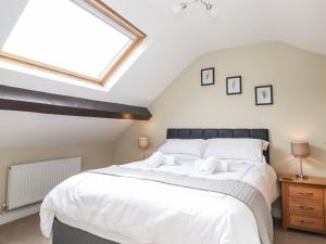 a bedroom with a large white bed with a skylight at Wansfell Loft in Ambleside