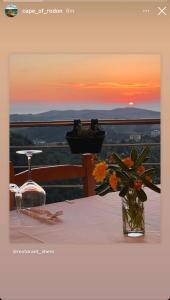 a table with a vase of flowers and a sunset at Restorant Hotel Xheni in Durrës