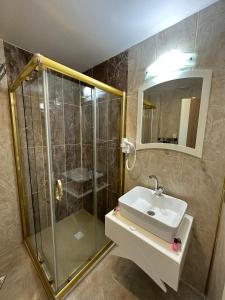 y baño con ducha, lavabo y espejo. en GrandPazarcıkOtel, 