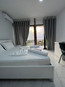 uma cama branca num quarto com uma grande janela em Restorant Hotel Xheni em Durrës