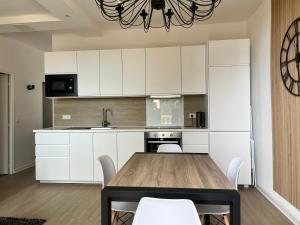 a kitchen with a wooden table and white cabinets at Coté Jardin est un spacieux et lumineux T3, entièrement rénové, à 2 pas de l'Hérault et à 10min du bord de mer Proche du centre historique et du fabuleux château Laurens, vous apprécierez le calme de sa belle terrasse et la vue superbe sur le jardin in Agde