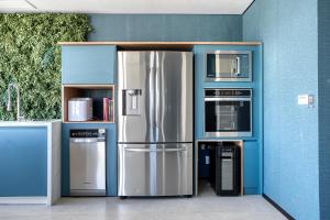 a kitchen with a stainless steel refrigerator and microwaves at Tabas - Pivô Match Jardins - Cravinhos in Sao Paulo