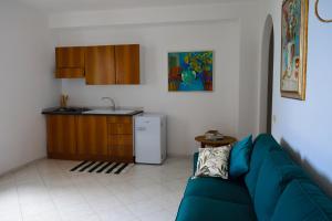 a living room with a blue couch and a kitchen at IL GIARDINO SELVATICO DI SUCCELLARIO - APARTMENTS in Ischia