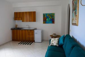 a living room with a blue couch and a kitchen at IL GIARDINO SELVATICO DI SUCCELLARIO - APARTMENTS in Ischia +18 photos
