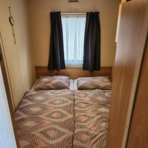a bed in a small room with a window at Mobilný domček na brehu Liptovskej Mary 