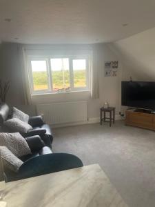 a living room with a couch and a flat screen tv at New Forest View in Beaulieu