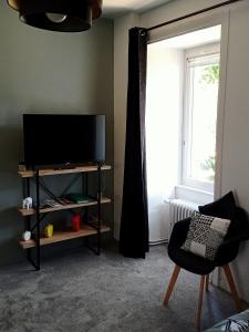 a living room with a tv and a chair and a window at Chambres d'hôtes du Couesnon in Saint-Ouen-des-Alleux