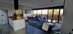 uma sala de estar com dois sofás azuis e uma cozinha em Casa Cuartel Centenillo - Alojamientos Rurales en Sierra Morena em El Centenillo