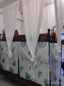Una cama con cortinas blancas. en Phangan Hostel Haadrin Homestay, en Haad Rin